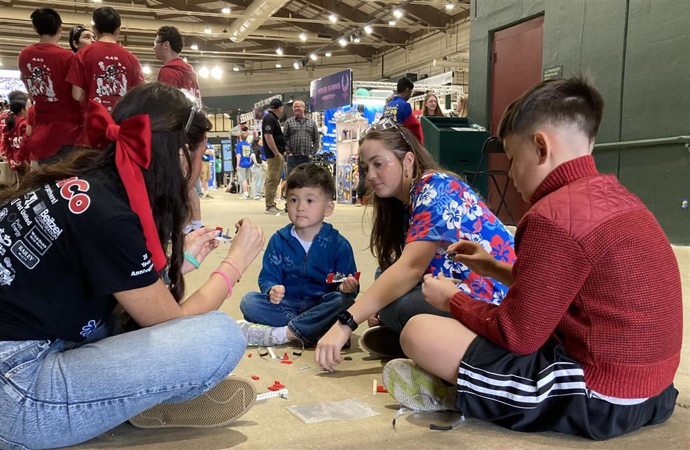 Image of two GaCo team members sharing a lesson with two younger children.